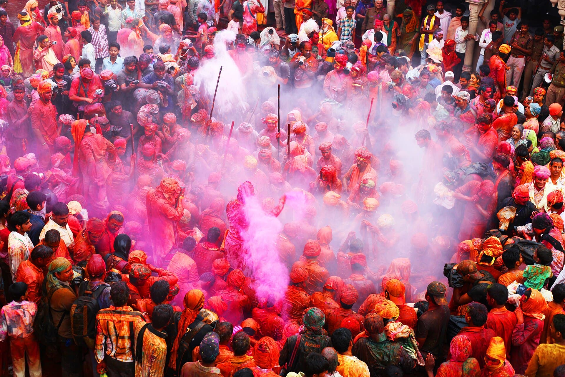 Crowds during Holi celebrations with colored powders in the air